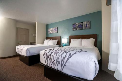 Habitación de hotel con 2 camas con sábanas blancas en Sleep Inn near Outlets en Myrtle Beach