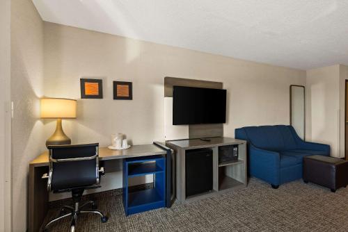 a hotel room with a desk and a tv and a chair at Comfort Inn Huntington Near University in Huntington