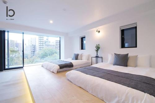 een slaapkamer met twee bedden en een groot raam bij b hotel Heiwaodori 201 - New Apt in Famous Hiroshima Dori Max 6p in Hiroshima