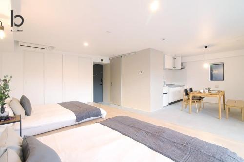 a bedroom with two beds and a table and a kitchen at b hotel Heiwaodori 201 - New Apt in Famous Hiroshima Dori Max 6p in Hiroshima