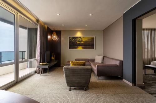 a living room with a couch and a chair and a window at Radisson Blu Okoume Palace Hotel, Libreville in Libreville