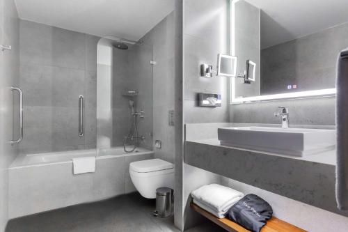 a bathroom with a sink and a toilet and a mirror at Radisson Blu Hotel, Tashkent in Tashkent