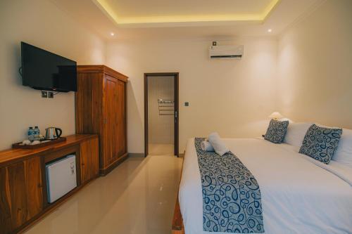 a bedroom with a bed and a flat screen tv at Cucukan Beach Guest House in Gianyar