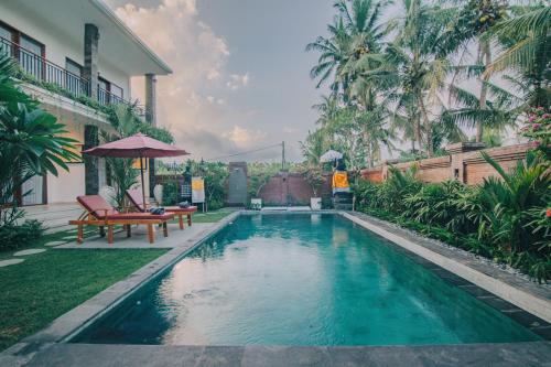 a swimming pool with a bench and an umbrella at Cucukan Beach Guest House in Gianyar