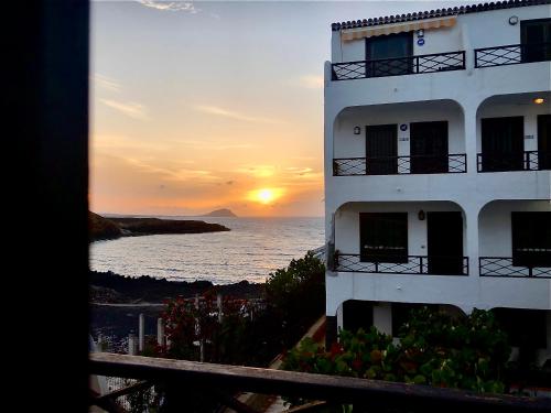 un bâtiment avec un coucher de soleil en face de l'océan dans l'établissement Sasha Tenerife, à Costa del Silencio