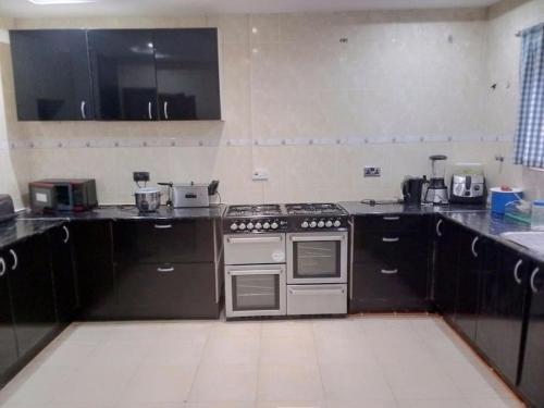 a kitchen with black cabinets and a stove at Cheerful and peaceful 4-bedrooms house in Koforidua
