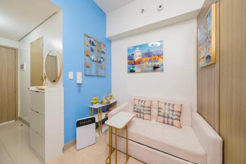 a room with a white couch and a blue wall at MALL OF ASIA Condo with Balcony Facing Pool @ Shore2 in Manila