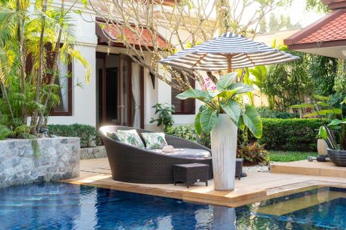a chair and an umbrella next to a pool at Saitaan Villa Dennapa Bang Tao Beach in Bang Tao Beach