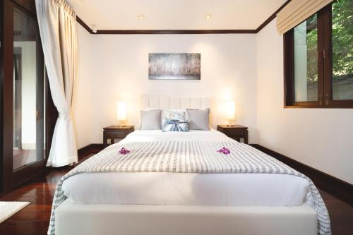 a bedroom with a large white bed with two lamps at Saitaan Villa Dennapa Bang Tao Beach in Bang Tao Beach