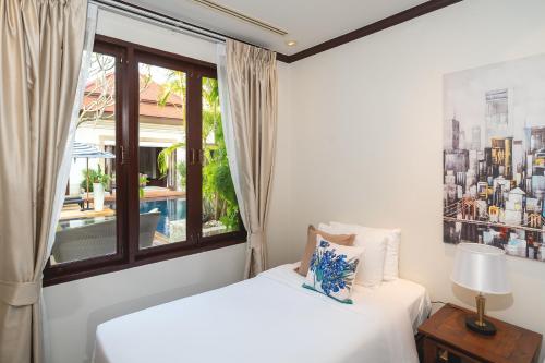 two beds in a room with a window at Saitaan Villa Dennapa Bang Tao Beach in Bang Tao Beach
