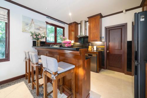 a kitchen with a bar with chairs and a refrigerator at Saitaan Villa Dennapa Bang Tao Beach in Bang Tao Beach