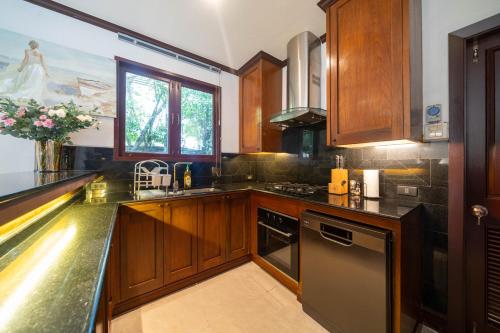 a kitchen with wooden cabinets and a counter top at Saitaan Villa Dennapa Bang Tao Beach in Bang Tao Beach