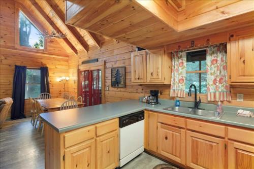 a kitchen with wooden cabinets and a table in a cabin at 5br Retreat With Hot Tub, Fireplace & Game Room! in Pigeon Forge