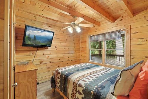 a bedroom with a bed and a flat screen tv at 5br Retreat With Hot Tub, Fireplace & Game Room! in Pigeon Forge