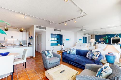 a living room with a blue couch and a kitchen at Galvestonian 710 in Galveston