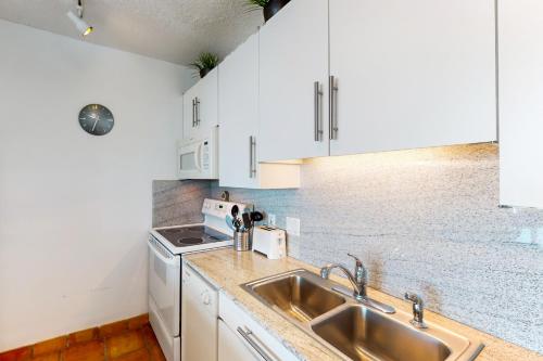 a kitchen with white cabinets and a sink at Galvestonian 710 in Galveston