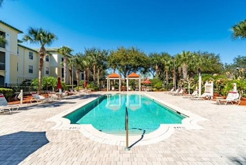 a swimming pool at a resort with chairs and trees at Incredible apartment just 15 minutes from Disney in Kissimmee