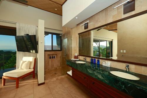 ein Badezimmer mit einem Waschbecken, einem Spiegel und einem Stuhl in der Unterkunft Hotel Three Sixty - Adults Only in Ojochal