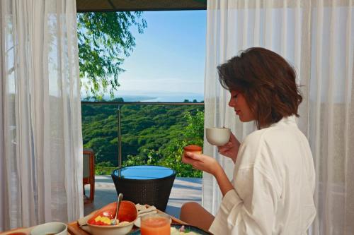 a woman sitting at a table with a glass of wine at Hotel Three Sixty - Adults Only in Ojochal