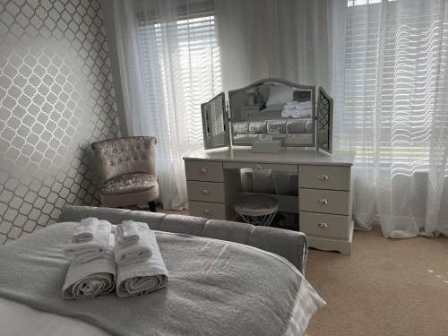 a bedroom with a bed and a dresser and towels at Fair Green B&B in Ballygawley