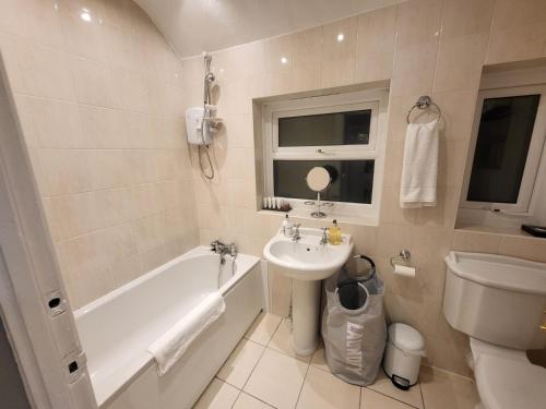 a bathroom with a sink and a tub and a toilet at Garland Modern House With Parking & Garden in Borehamwood