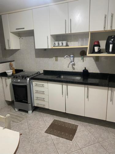 Una cocina con gabinetes blancos, un fregadero y una estufa. en Apartamento pé na Areia de Frente para o Mar, en Arraial do Cabo