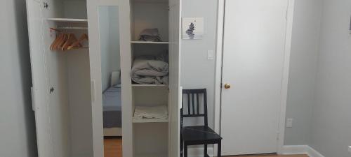 Cette chambre comprend un placard avec des étagères blanches et une chaise. dans l'établissement High Park Single room with exclusive washroom and kitchen for solo travelers, à Toronto