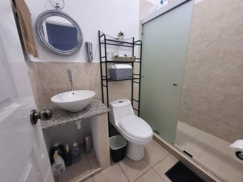 uma casa de banho com um WC, um lavatório e um espelho. em Max´s House em Ahuachapán
