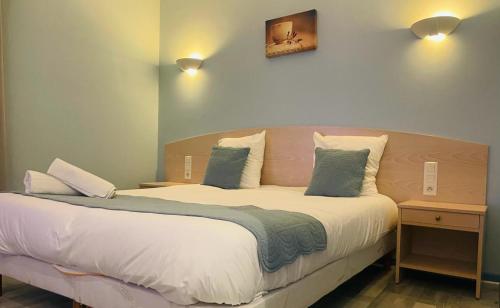 ein Schlafzimmer mit einem großen Bett mit zwei Kissen in der Unterkunft Hôtel Les Demoiselles in Essoyes