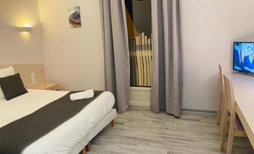 Schlafzimmer mit einem Bett, einem TV und einem Fenster in der Unterkunft Hôtel Les Demoiselles in Essoyes