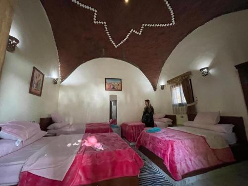 アスワンにあるMaghrabi's Guest houseのベッド2台付きの部屋に立つ女性