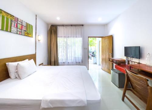 a bedroom with a white bed and a television at Lara Homestay in Kuta Lombok