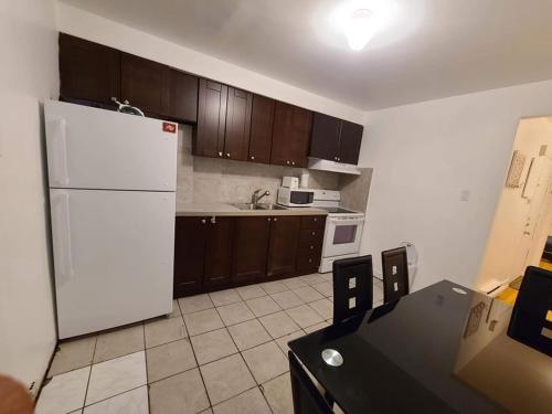 eine Küche mit einem weißen Kühlschrank und Holzschränken in der Unterkunft 425$ 7nights // Full Kitchen // Room B in Montreal