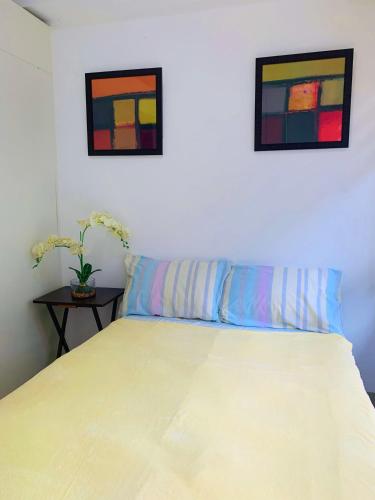 a bedroom with a bed with two pictures on the wall at BRENT CONDO UNIT WITH FREE PARKING & NETFLIX in Tagaytay