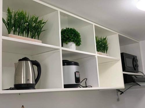 a white shelf with potted plants on it at BRENT CONDO UNIT WITH FREE PARKING & NETFLIX in Tagaytay