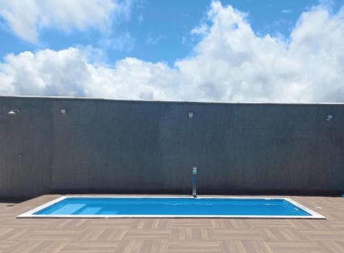 a blue swimming pool in front of a wall at Nossa Casa com Piscina in Guarapari