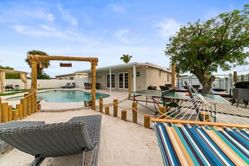 a backyard with a pool and chairs and a house at Paradise Villa! Heated Pool, Game Room, Beach near! in West Palm Beach