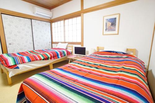 1 Schlafzimmer mit 2 Betten in einem Zimmer mit Fenstern in der Unterkunft Takamatsu Guest House Akane in Takamatsu