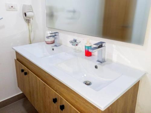 ein Badezimmer mit einem weißen Waschbecken und einem Spiegel in der Unterkunft Bella Place in Santiago de los Caballeros