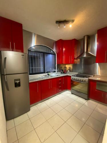 a kitchen with red cabinets and a stainless steel refrigerator at HERMOSA CASA PRIVADA EN FRACC VALLE VERDE, AL SUR DE LA CIUDAD. in Tapachula