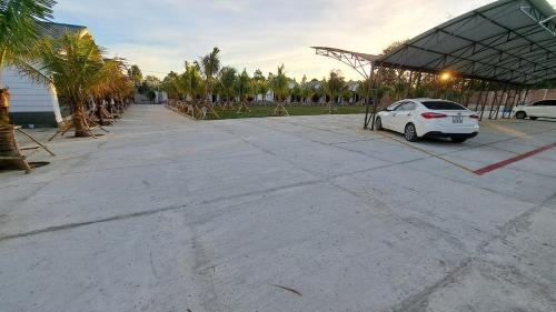 a white car parked in a parking lot with palm trees at Konklor Hotel in Kon Tum