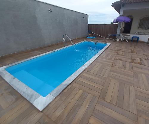 een zwembad in een tuin met een houten vloer bij Nossa Casa com Piscina in Guarapari
