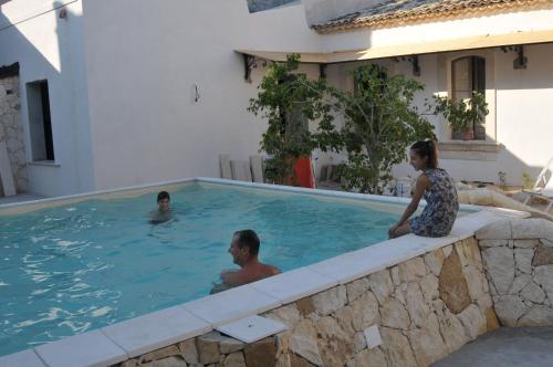 a man and a woman sitting in a swimming pool at Morfeo Charming Rooms & Relax in Avola