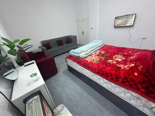 a room with a bed with a red blanket and a couch at Furnished studio with private entrance in Irbid