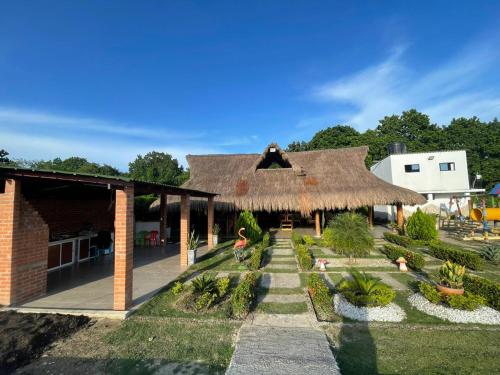 un edificio con tetto di paglia e giardino di CASA FINCA CERCANA A CTG a Turbaco