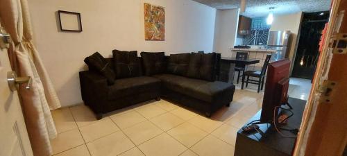 a living room with a brown couch and a kitchen at Departamento cerca de la playa in Puerto Vallarta