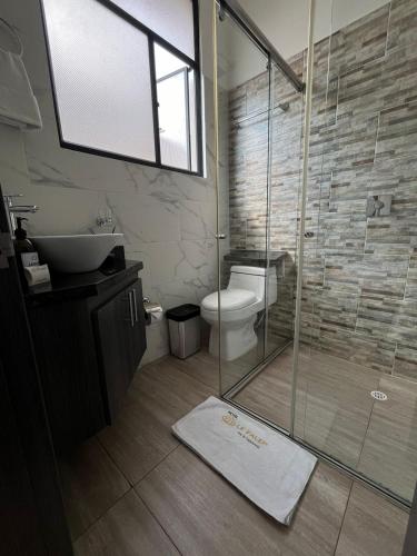 a bathroom with a toilet and a glass shower at Hotel Le Falep & Spa in Anapoima