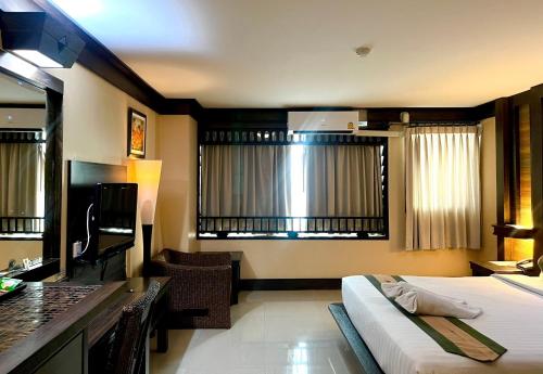 Habitación de hotel con cama, escritorio y habitación en Ruean Phae Royal Park Hotel en Phitsanulok