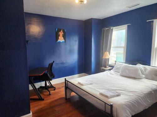 een slaapkamer met blauwe muren en een bed en een bureau bij spacious and indulging in Meriden