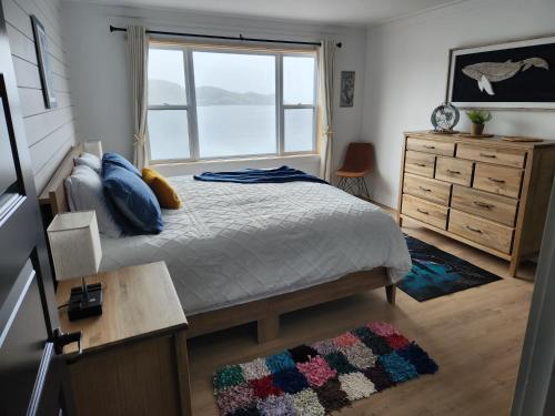 a bedroom with a bed with a window and a dresser at Seaclusion Twillingate in Twillingate